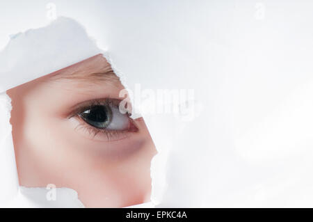 Child eye looking through a hole in paper Stock Photo