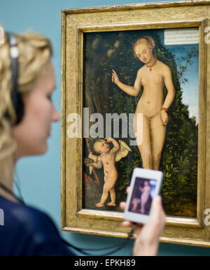 A woman looks at the painting 'Venus with Cupid the honey thief' (after 1537) by Lucas Cranach the Elder with a specially made audio guide in her hand prior to the opening of the exhibition 'Between Venus and Luther: Cranach's Media of Temptation' at the Germanisches Nationalmuseum (Germanic National Museum) in Nuremberg, Germany, 18 May 2015. The museum puts the works of Lucas Cranach the Elder (1472 - 1553) into focus on occasion of the Luther decade. About twenty works which are permanently on exhibition are explained in a cultural-historical context in a new presentation. Photo: Daniel Kar Stock Photo