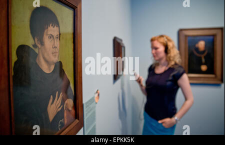 A woman holds a specially made audio guide in her hand as she stands next to the portrait of Martin Luther as an Augustinian Monk (after 1546) by Lucas Cranach the Elder prior to the opening of the exhibition 'Between Venus and Luther: Cranach's Media of Temptation' at the Germanisches Nationalmuseum (Germanic National Museum) in Nuremberg, Germany, 18 May 2015. The museum puts the works of Lucas Cranach the Elder (1472 - 1553) into focus on occasion of the Luther decade. About twenty works which are permanently on exhibition are explained in a cultural-historical context in a new presentation Stock Photo