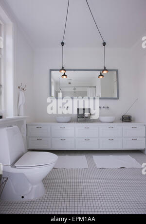 Double basin and toilet with mirror in tiled bathroom of Hanne Davidsen home renovation, Silkesborg, Denmark. Stock Photo