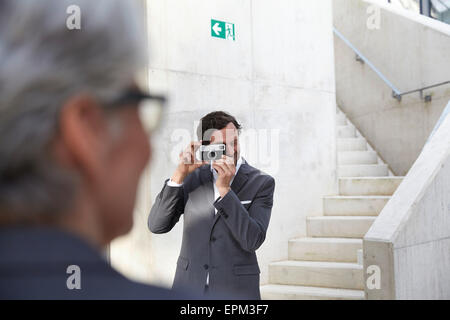 Businessman photographing his female colleague with camera Stock Photo