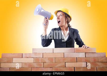 Woman builder with loudspeaker on white Stock Photo