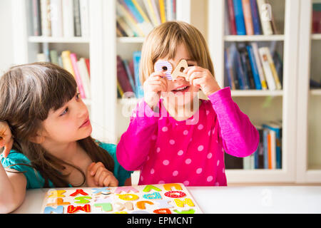 Two sisters with with wooden alphabet puzzle Stock Photo