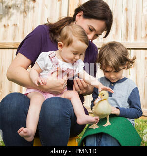 A woman and two children, with a young duckling. Stock Photo