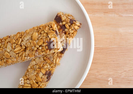 Close view of two chocolate chip granola bars on a plate atop a wood table top. Stock Photo