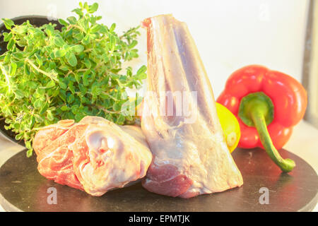 Lamb shank, in front of herbs and vegetables Stock Photo