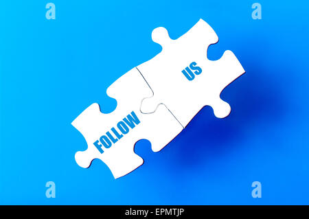 Connected puzzle pieces with text FOLLOW US  isolated over blue background, with copy space available. Business concept image. Stock Photo