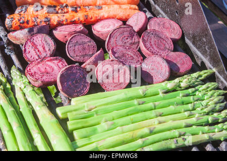 Grilling purple beetroots, orange carrots and green aspargus Stock Photo