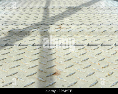 Close view of a steel non-slip walkway with the shadows of the railings. Stock Photo