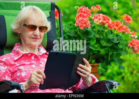 Senior Caucasian Woman reading eBook on Kindle or Tablet Stock Photo