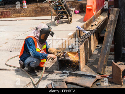 Construction worker welding a steel beam on a construction site, Bangkok, Thailand Stock Photo
