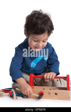 Two year old boy is playing with wooden tools on white background Stock Photo