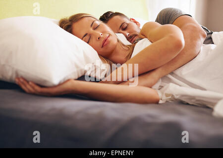 Image of a young couple together sleeping comfortably on the bed. Young man and woman lying asleep. Stock Photo