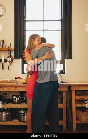 Young couple in love hugging each other. Young man and woman in kitchen embracing. Stock Photo