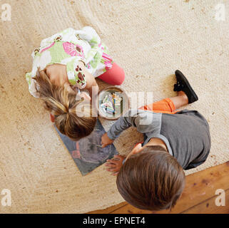 Top view of two little kids sitting on floor drawing with color chalks. Stock Photo