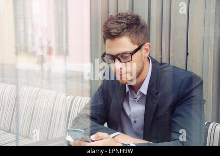 young attractive businessman using device and drinking espresso coffee in the city cafe during lunch time, business concept Stock Photo