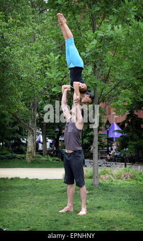 An athletic fit couple do acro yoga exercises in Washington Square Park in New York City Stock Photo