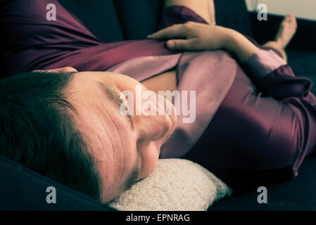 Man lying and resting on sofa at home. He is sleeping with his head on a pillow. Stock Photo