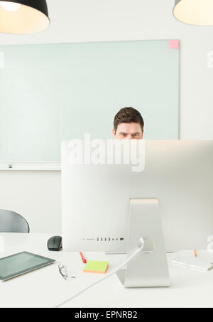 Businessman sitting by desk, working with computer in office. Stock Photo
