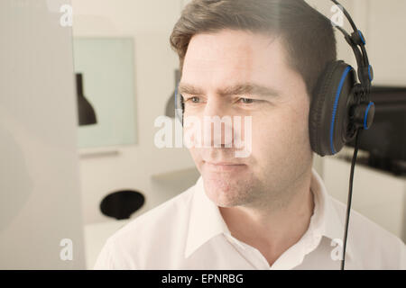 Man with headphones in office listening to music. Stock Photo