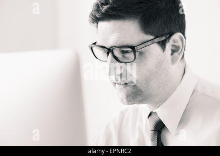 Businessman sitting by desk, working with computer in office. Stock Photo