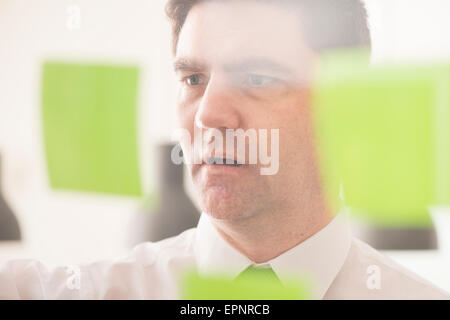 Businessman looking at glass wall with adhesive notes. Conceptual image of business planning. Stock Photo