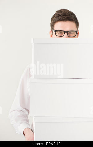 Businessman carrying white boxes used for moving. Conceptual image of business relocation, startup or change. Stock Photo