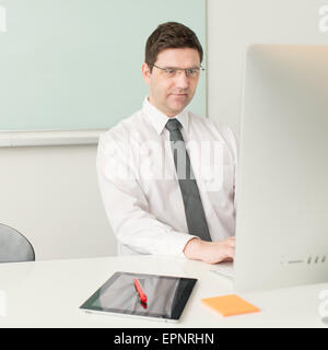 Businessman sitting by desk, working with computer in office. Stock Photo