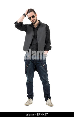 Serious young bearded man running fingers through hair looking at camera. Full body length portrait isolated over white backgrou Stock Photo