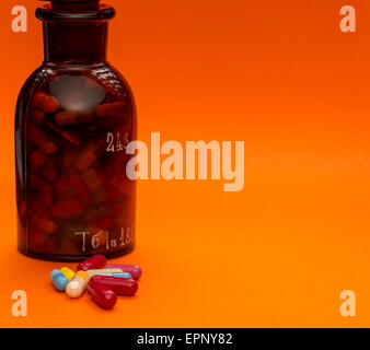 Glass bottle with pills and sopy space on orange background Stock Photo