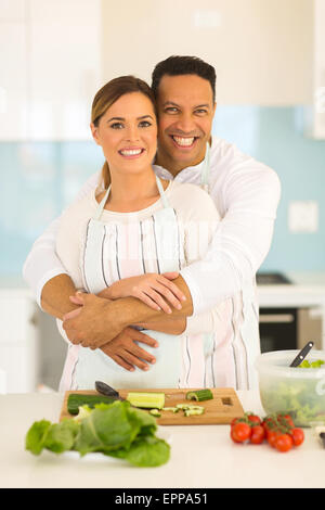 romantic couple embracing in kitchen while preparing dinner Stock Photo