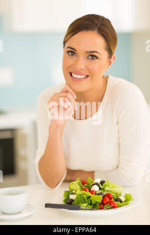 attractive woman having green salad in kitchen Stock Photo