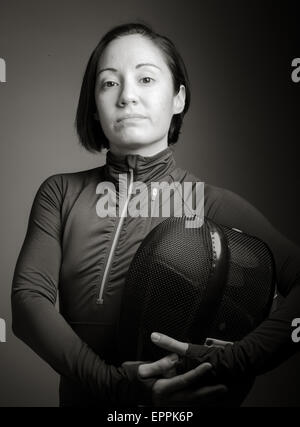 Portrait of a female fencer wearing fencing uniform and holding a mask isolated on gray background Stock Photo