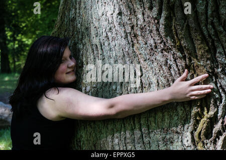 Young Woman hugging an old Oak Tree with Copy space Stock Photo