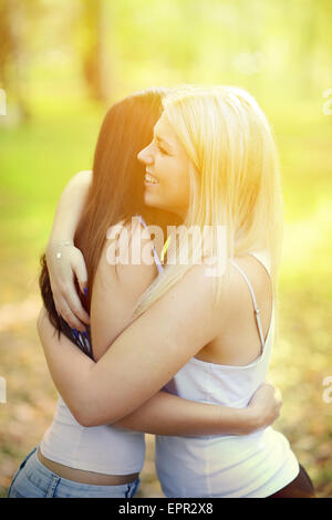 Close up portrait of two happy girls hugging outdoors