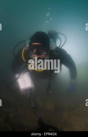 Underwater survey. Scuba diver uses a metal detector to help search for buried objects. In this case a hoard of 2000 gold coins Stock Photo