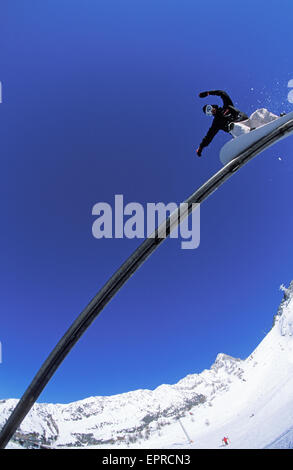 A young man rides a rail on his snowboard. Stock Photo
