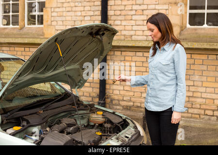 young woman checking the oil gage on her car Stock Photo