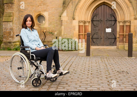 a sad young woman in a wheelchair waiting outside a church Stock Photo