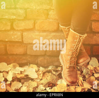 Conceptual image of legs in boots on the autumn leaves - Walking in nature Stock Photo