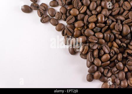 Closeup overhead of loose roasted coffee beans on white cardboard with copyspace