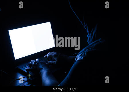 Single solitary computer hacker works in the dark committing crime Stock Photo
