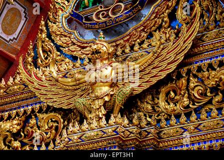 Bangkok, Thailand:  An immense gilded Phoenix with open wings decorates an Ubosot sanctuary hall tympanum at Wat Hua Lamphong Stock Photo