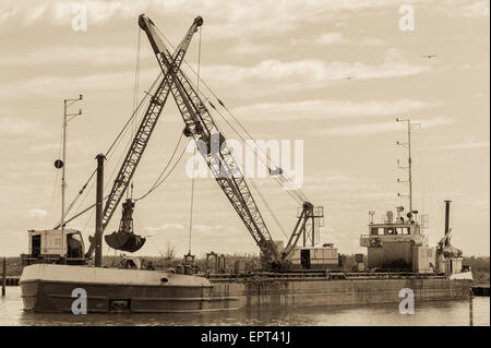 Effect vintage. Small dredge the marina, which is cleaning a navigation channel Stock Photo