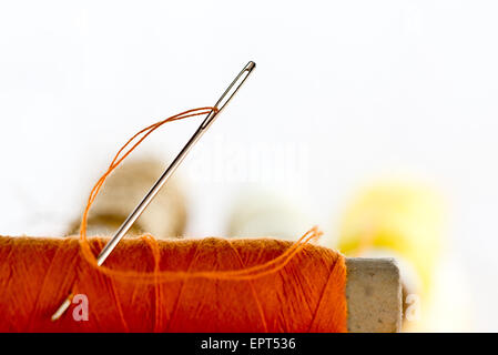 needles and orange color thread on the white background Stock Photo