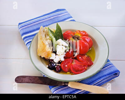 Fresh Salad with Heirloom Tomatoes, Kalamata Olives, Baguette, Basil and Cheese on White Table, Outdoors, Canada Stock Photo