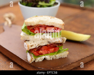 Bacon Lettuce and Tomato Sandwich with Pickle and Salad on Breadboard, Studio Shot Stock Photo