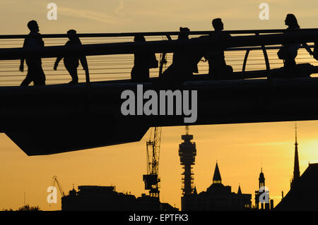 Pedestrians in silhouette on the Millennium Bridge, London UK, at dusk, with buildings in background Stock Photo