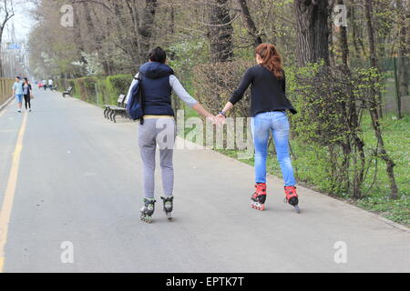 Two ladies holding hands whilst rollerskating, Bucharest, Romania Stock Photo