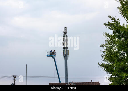 Two men working from a lift bucket on a mobile or cell phone tower in Modesto California Stock Photo